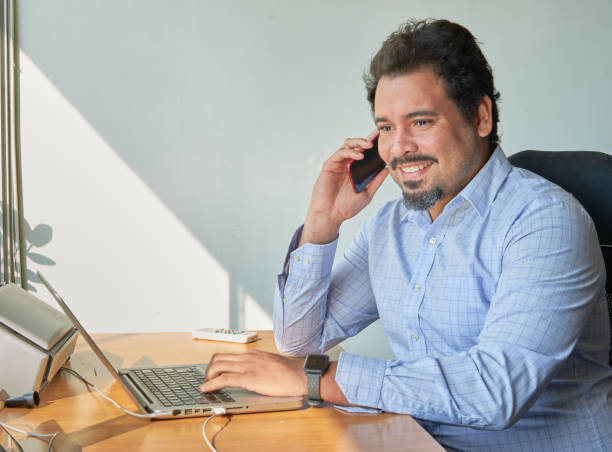 Latin businessman at desk with laptop in home office