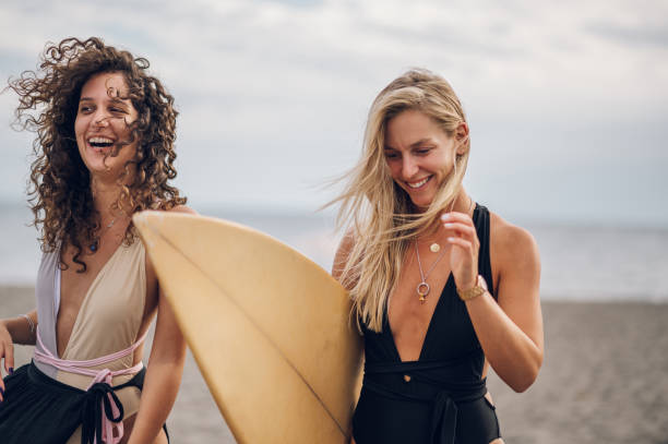 istock Two beautiful woman friends posing with surfboard on a beach 1480176750