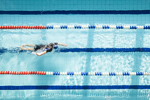 Top view shot of young man swimming laps in swimming pool. Male swimmer swimming the front crawl in a pool. swimming crawl.