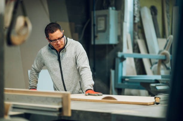 istock A craftsman in protective workwear is cutting wooden material on a saw in his workshop. 1480177328