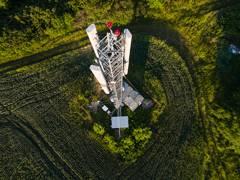 Drone view of telecommunications pylon in green agricultural field. Technology and Global Business.