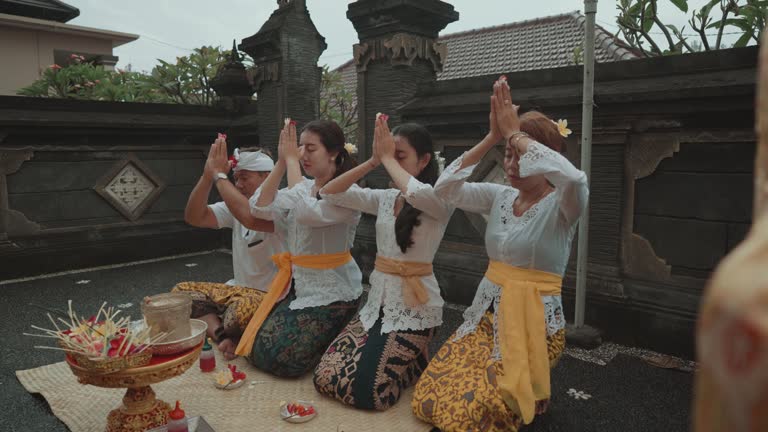 Balinese Family Performing Hindu Ritual Prayer Daily Offerings at Home Temple in Bali Indonesia Culture Religion