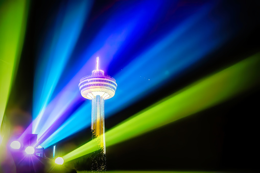 Niagara Falls, Ontario, Canada - May 27, 2013:  The Skylon Tower is a revolving restaurant and observation tower located in the heart of the Niagara Falls, Ontario tourist centre. A laser light show was captured in the foreground with the tower in the background dominating the constructed skyline in the area.