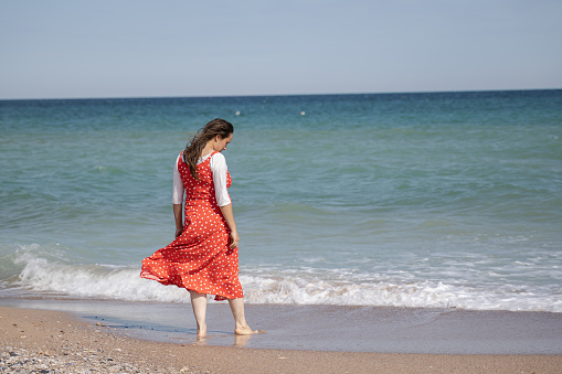 Solo travel at the seaside in autumn. Future mother enjoys the autumn sea.