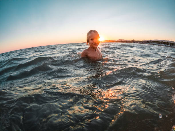 istock Boy Playing In The Sea At Sunset 1480182294