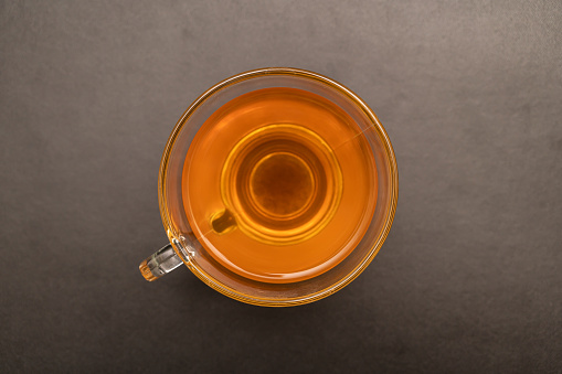 Glass cup of hot ginger tea on the black desk.