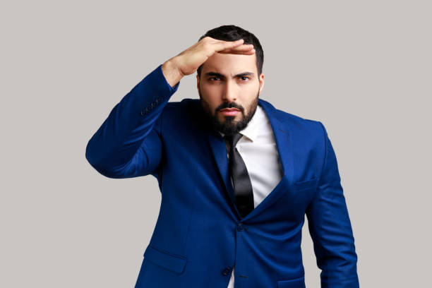 istock Serious concentrated bearded man watching far away with hand above eyes, looking forward to future. 1480182745
