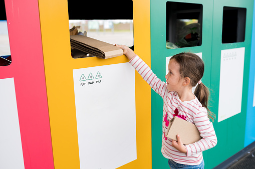 Girl dumping cardboard in bank for reduce, reuse, recycle. National Recycling Day. concept of care for the environment and build sustainable future.