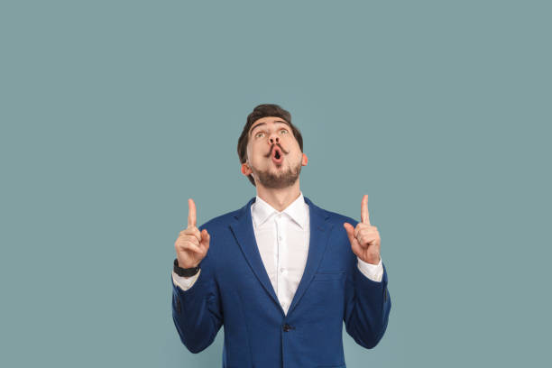 istock Amazed shocked surprised man standing pointing index finger up, showing advertisement area. 1480184655