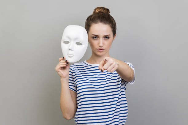 istock Woman holding white mask in hand, pointing finger to camera with serious expression. 1480184797
