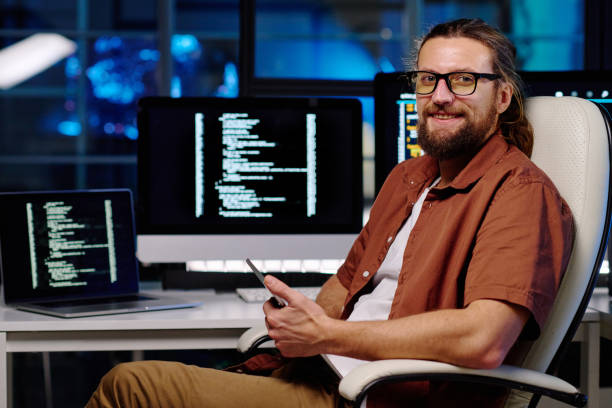istock Young smiling male IT engineer in eyeglasses using smartphone 1480186767
