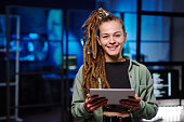 Young cheerful female IT manager with tablet looking at camera