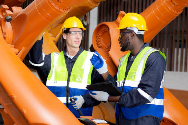 Two young engineer man meeting and explaining about robot arms technology intelligence and innovation at factory industrial, maintenance machine, people using digital tablet with examining robot. dos jóvenes ingenieros se reúnen y explican sobre la inteligencia tecnológica de los brazos robóticos y la innovación en la fábrica industrial, la máquina de mantenimiento, las personas que usan la tableta digital con el robot examinador.