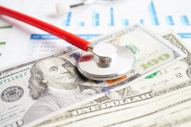 istock Stethoscope and US dollar banknotes on chart or graph paper, Financial, account, statistics and business data  medical health concept. 1480193984