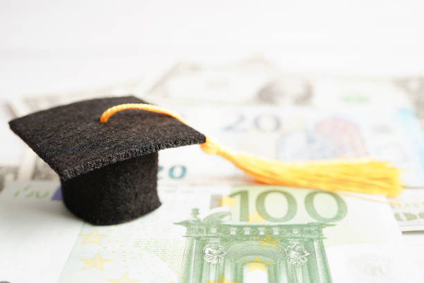 istock Graduation gap hat on Euro and US dollar banknotes money, Education study fee learning teach concept. 1480194610