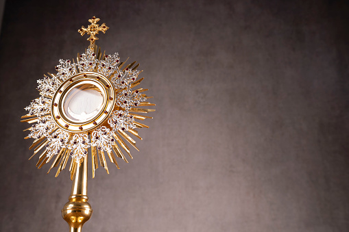 The monstrance and golden chalice on gray background.