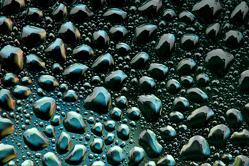 Water droplets on the glass with a green background. Drops of water.
