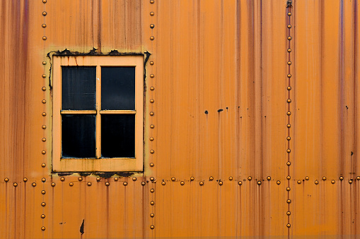 Old wooden window shutters of an european house with orange painted facade, vintage background.