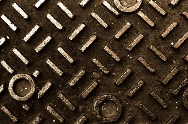 A toned black and white image of manhole cover.
