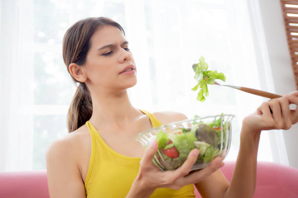 istock Young caucasian woman sitting on sofa eating vegetable salad while feeling dislike and expression disgusted, woman emotion frustrated with anorexia vegetarian and hate, nutrition food concept. 1480205969