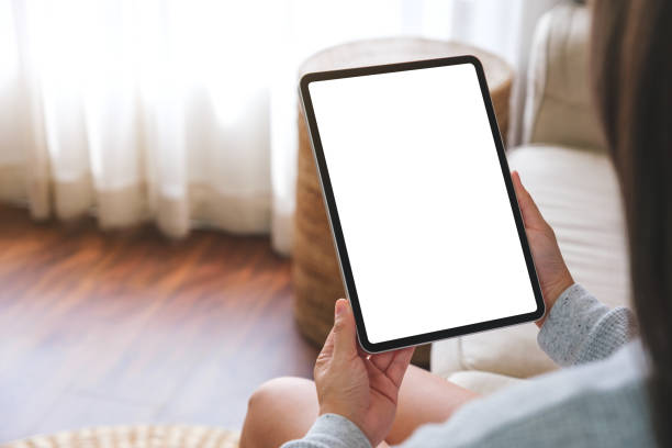 istock Mockup image of a woman holding digital tablet with blank desktop screen while lying on a sofa at home 1480208905