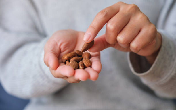 istock Closeup image of hands holding and picking up an almonds 1480208928