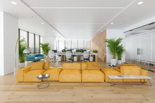 Modern Open Plan Office Space With Waiting Area, Meeting Room, Office Chairs, Tables, Computers And Potted Plants. Yellow Corner Sofa And Coffee Table In Waiting Area