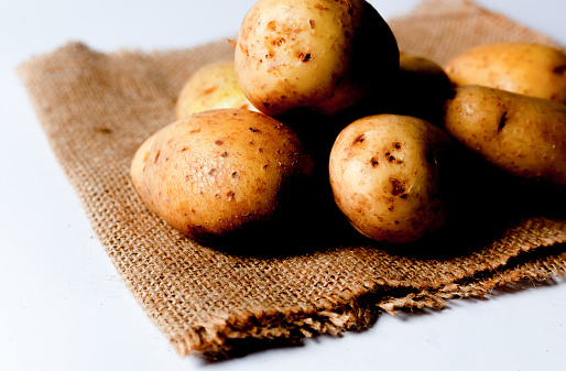 Raw potatoes on burlap mat isolated on white backgroun