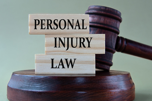 PERSONAL INJURY LAW - words on wooden blocks against the background of a judge's gavel with a stand.