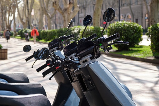 Close-up of several scooters for rent by the rental and sharing system on the street in the city. Infrastructure and improvement of urban life.