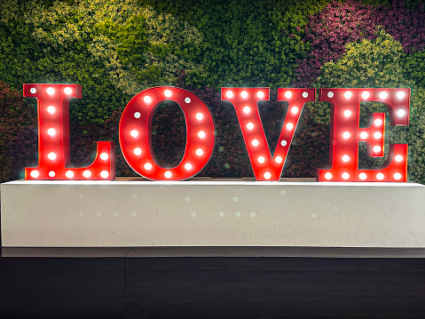 Stock photo showing an illuminated love sign, with the word 'LOVE' being spelt out by individual letters lit by bright white light bulbs.