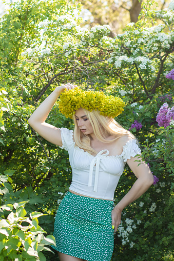 Beautiful woman in lilac Garden. Girl with yellow flower wreath in springtime. Gardening. Soft focus