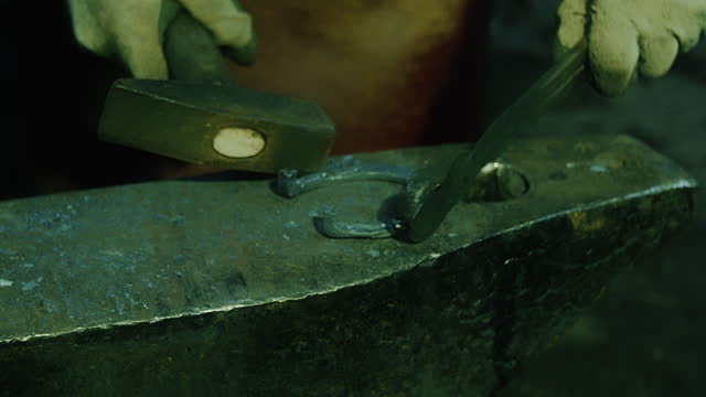 Blacksmith works with metal on the anvil