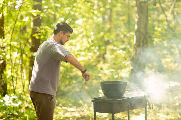 A man cooks in a cauldron on the grill