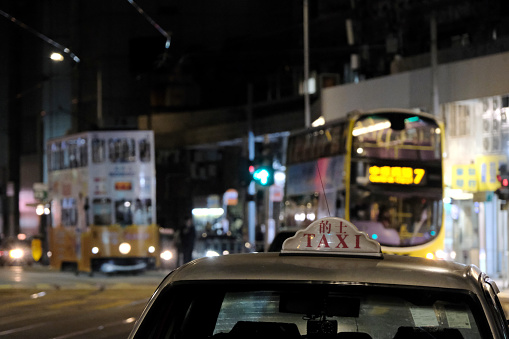 Taxi parked on the busy Des Voeux road by night in Sai Ying Pun, a residential area in the Western District, in the northwestern part of Hong Kong Island.