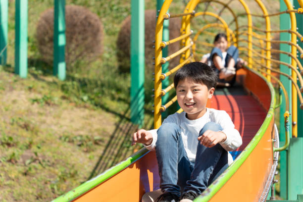istock Elementary school students playing on the slide in the park 1480230814