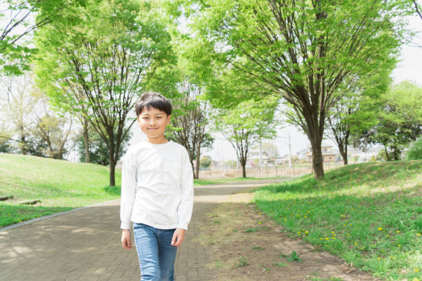 smiling boy walking in a park with fresh greenery smiling boy walking in a park with fresh greenery april 10 stock pictures, royalty-free photos & images