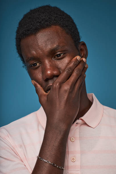 istock Closeup distressed black man covering mouth against blue background 1480238705