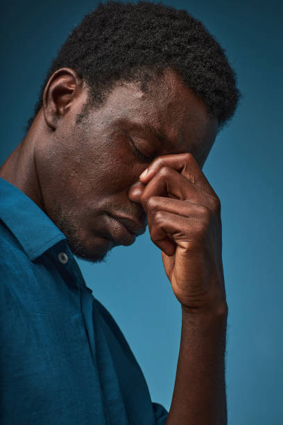 istock Stressed black man with eyes closed against blue background 1480238734