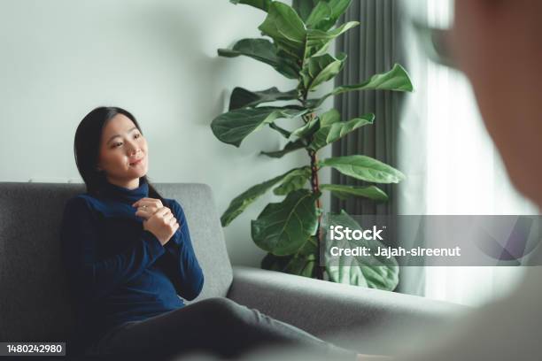 Asian Woman Talking With Psychologist About Problems After Married Sitting On Sofa In Counseling Office Stock Photo - Download Image Now