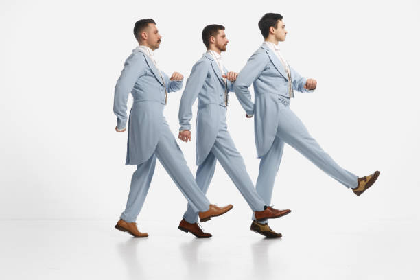 group of pensive men wearing old-fashioned clothes standing in a row and marching over white background. gentlemen - real people blue white friendship imagens e fotografias de stock