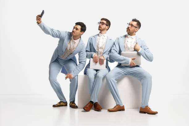 three men, partner wearing elegant clothes sitting in a row and taking selfie over white background. business meeting - real people blue white friendship imagens e fotografias de stock