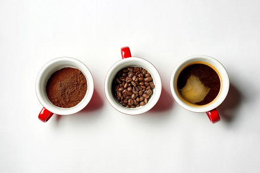 Ground coffee and coffee beans, espresso in cups on a white background. Three states of coffee
