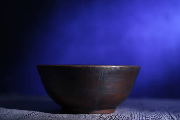 Empty clay pot bowl under the light with dark background