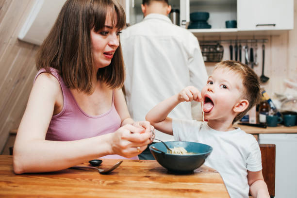 istock Mother with father feeding the child in the kitchen with pasta 1480249355