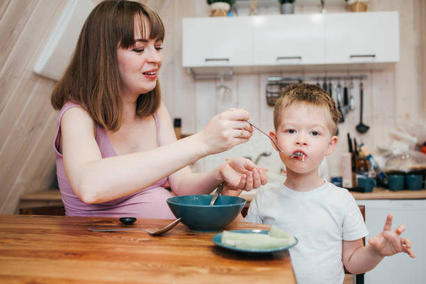 istock Cheerful child eating pasta in the kitchen with mom 1480249464