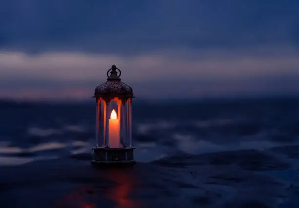 Ramadan Kareem, Arabic lantern with burning candle on sand beach with blurry sunset sky background.Image for Festive greeting card,invitation for Muslim holy month,Eid Mubarak,Eid al Adha,Eid al Fitr