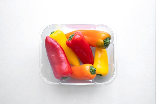 Red , yellow and orange peppers in bowl on white background