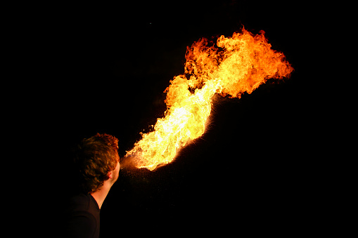 Beautiful flame out of fire-eater's mouth. On black background.