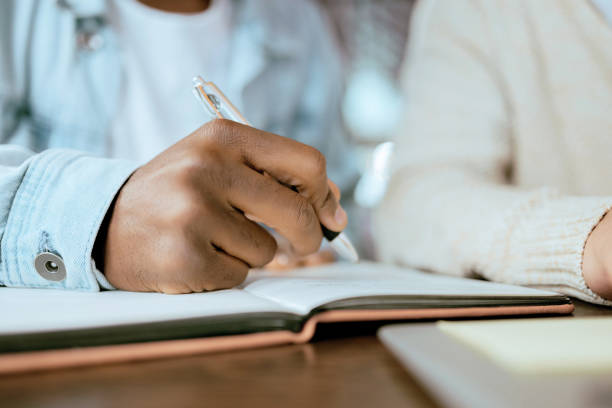 istock Closeup, black man hand and writing in notebook at desk for studying, planning and support for goals. Student men, book and pen for brainstorming, vision or thinking together for university success 1480254700